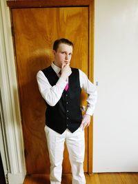 Portrait of teenage boy with hand on chin wearing suit at home