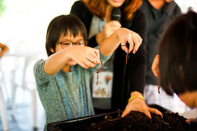 Girl holding earthworms over container
