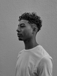 Portrait of young man looking away against wall