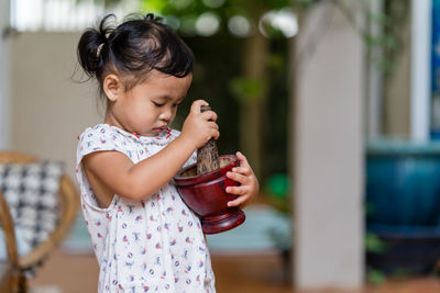 Cute girl holding mortar and pestle at home