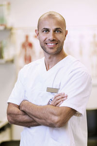 Portrait of confident orthopedic surgeon standing arms crossed in clinic