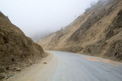 Empty road amidst mountains against sky