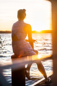 Rear view of woman looking at sea during sunset