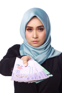 Portrait of woman holding paper currency while standing white background