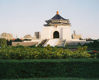 Temple by building against clear sky