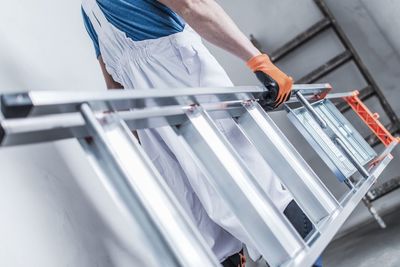 Close-up of man carrying ladder