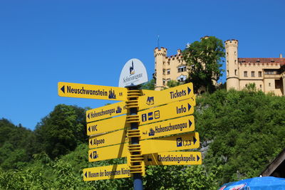 Low angle view of information sign against clear blue sky