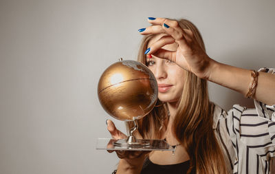 Woman looking at globe against gray background