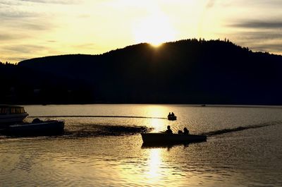 Silhouette boat in lake against sky during sunset