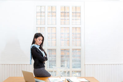 Side view of a young woman sitting on table