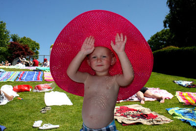 Portrait of shirtless boy wearing red hat at park