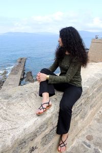 Woman standing by sea against sky