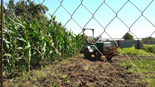 Tractor on field seen through chainlink fence