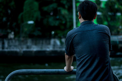 Rear view of mid adult man standing by railing