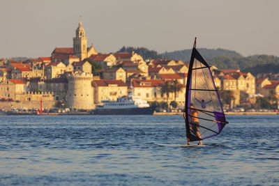 Sailboat sailing on sea against buildings in city