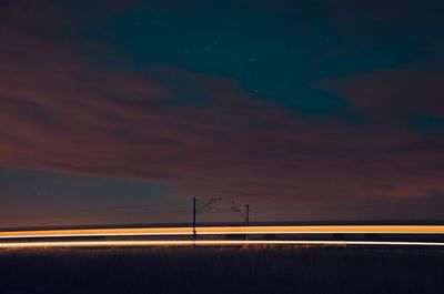 Light trails on road against sky at night