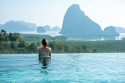 Rear view of man in swimming pool against sea