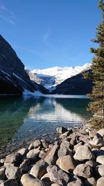 Scenic view of lake by snowcapped mountains against sky