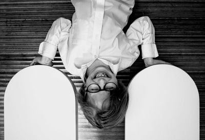 Upside down image boy holding built structure while standing against shutter