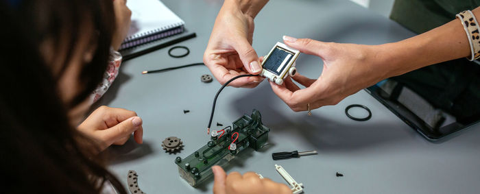 Female teacher explaining to student how connect a solar panel on electrical circuit