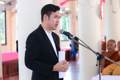 Side view of man giving speech on microphone during event