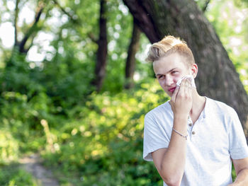 Young man smoking against tree trunk