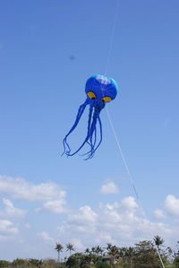 Low angle view of balloons flying against blue sky