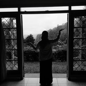 Rear view of silhouette woman standing at door