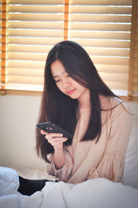 Young woman using mobile phone at home