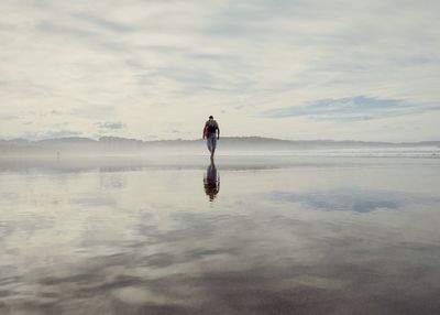 Man standing in sea against sky