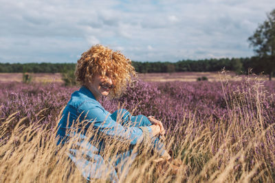 Rear view of woman standing amidst wheat field against sky