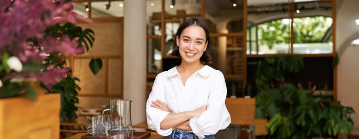 Portrait of smiling young woman standing in cafe