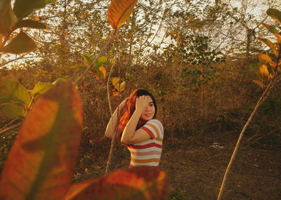 Smiling woman standing on land against trees in forest