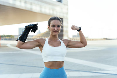 Smiling woman with arm prosthesis flexing muscles