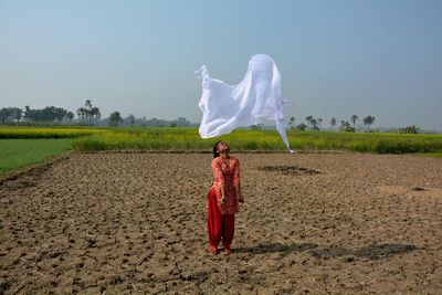 Full length of woman standing on field against sky