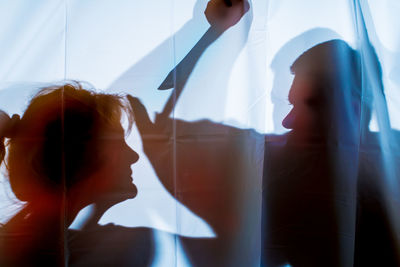 Shadow of man aiming knife on woman