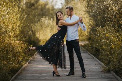 Couple dancing while standing on footpath amidst plants