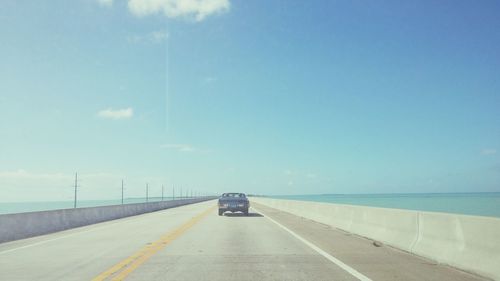 Car on road leading towards sea