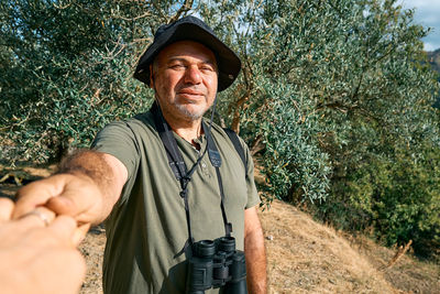 Follow me. bearded man hold and pull the photographer's hand leading her on olive grove in mountain