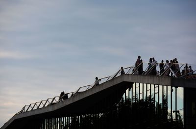 Low angle view of people on bridge against sky
