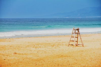 Ladder at beach against blue sky