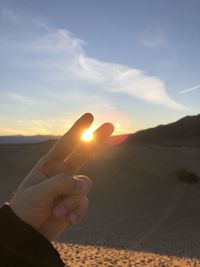 Midsection of person holding sun during sunset