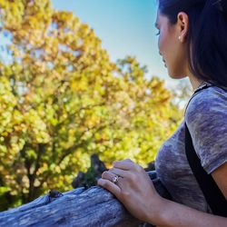 Side view of young woman against trees