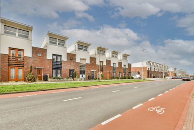 Empty road by buildings against sky