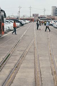 People walking on railroad tracks in city