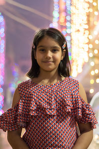 Portrait of smiling girl standing against illuminated lights