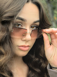 Close portrait of a young brunette woman, with brown eyes, long hair and sunglasses