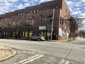 Cars on street by buildings in city against sky