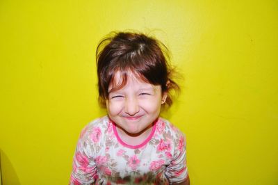 Portrait of smiling girl against yellow wall