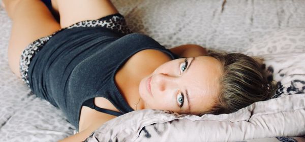 Portrait of young woman lying on bed at home